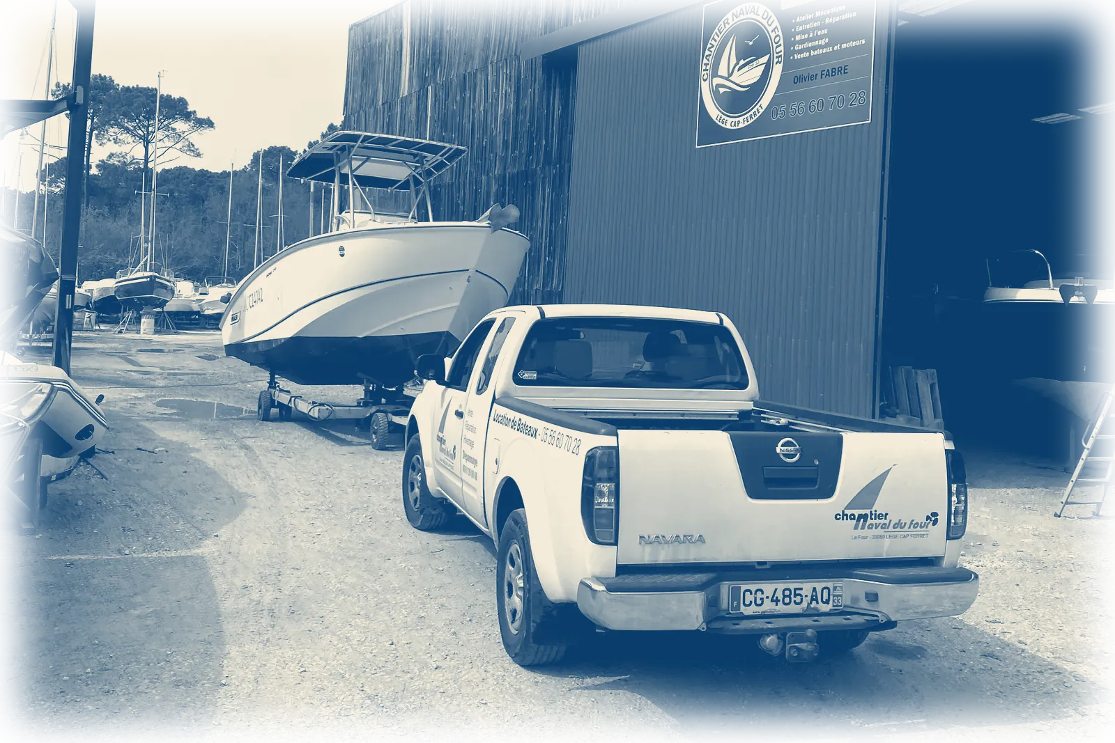 le hangar du chantier, son panneau et le pick-up, un bateau sur sa remorque